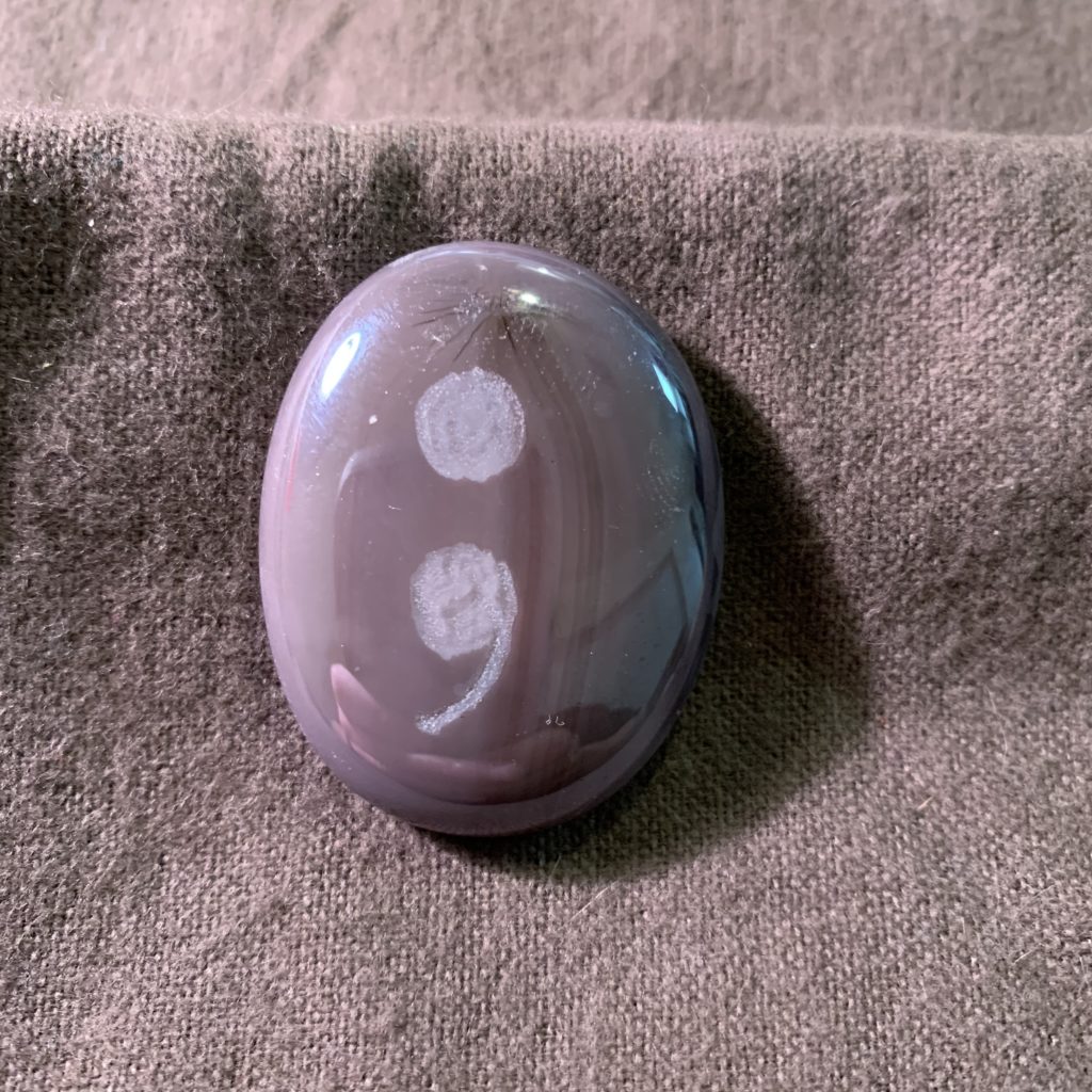 Purple MyRockAndI worry stone with a semi colon engraved on it